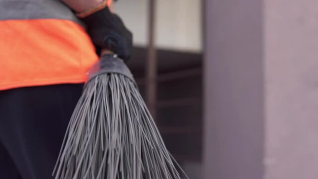 A cleaning lady is walking down the street with a broom. Cleanliness and order in the yard during quarantine depends on the janitor.