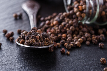 aromatic black pepper on a dark stone background