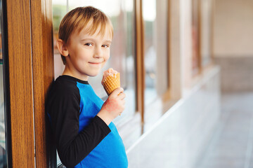 Happy boy eating ice cream at the city centre. Happy childhood.