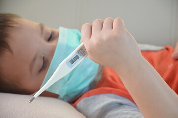 Sick Teenager with Thermometer in the Bed. fever, virus. waiting for a doctor. is treated at home. mom treats son