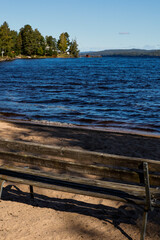 Fototapeta na wymiar Torsby, Sweden A little beach and bench on the Mellan-Fryken body of water.