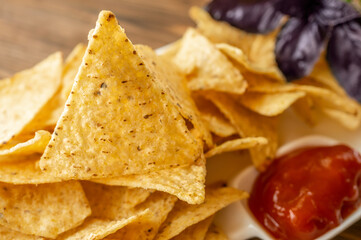 nachos and tomato sauce on a wooden background. Mexican national snack close-up