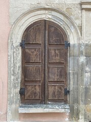 Altes Fenster mit Rundbogen, von Holzläden verschlossen