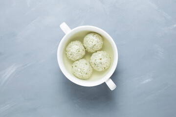 Diet meatballs made from Turkey breast or chicken with chopped spinach in bone broth. Gray background, top view, copy space. Healthy product with collagen that provides the body with amino acids
