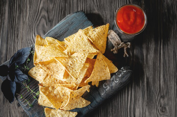 nachos and tomato sauce on a wooden background. Mexican national snack top view. copy space