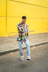 Chico atractivo joven posando delante de pared amarilla con estilo vintage