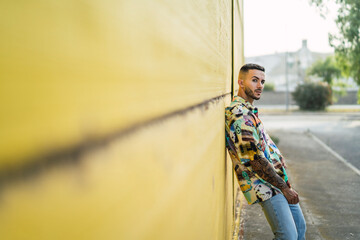 Chico atractivo joven posando delante de pared amarilla con estilo vintage