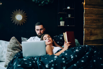 Couple lying together in bed and watching laptop