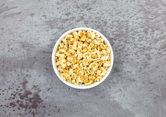 Honey puffed wheat in a bowl on a mottled gray background