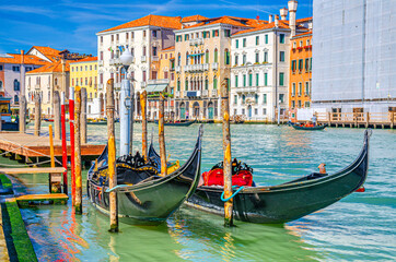Fototapeta na wymiar Gondolas traditional boats moored in wooden pier dock of Grand Canal waterway in Venice historical city centre with row of colorful buildings Venetian architecture. Veneto Region, Northern Italy.
