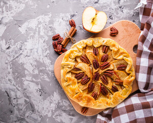crispy apple galette with pecans on a rustic wooden background