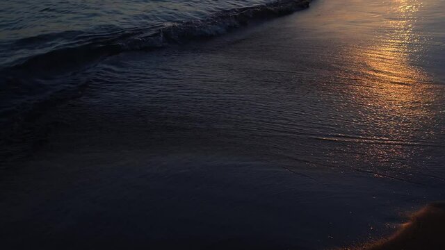 Sunset on beautiful sandy beach. Soft waves of sea water splashing at seashore softly and peacefully.
