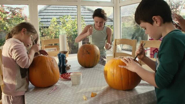 Young sibling children carving pumpkins for Halloween decorations