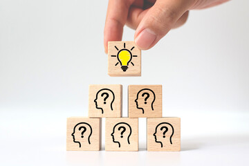 Concept creative idea and innovation. Hand picked wooden cube block with light bulb icon on top pyramid and head human symbol