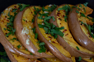 Pumpkin slices in a glass baking dish. Sprinkled with garlic and green parsley seasoning. Yummy fall dish.