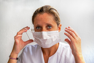 Portrait d'une jeune femme du personnel médical qui met un masque chirurgical