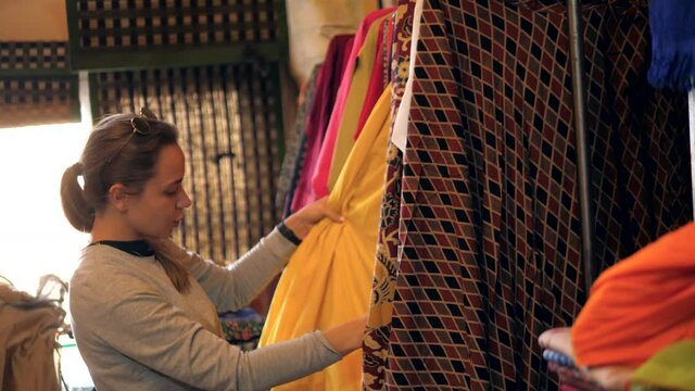 woman shopping on the indian market in the india vacation choosing colorful dress buying at street store shop for herself and friends and family as presents.