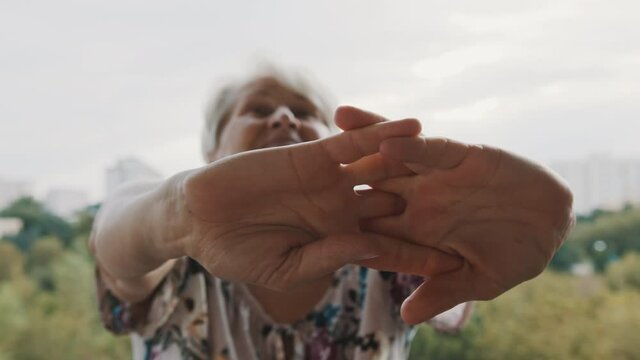 Elderly woman suffering from pain in hand, stratching hands and snapping her fingers. High quality 4k footage