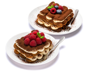 two portions of Classic tiramisu dessert with raspberries and blueberries on ceramic plate isolated on white with clipping path
