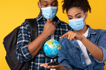 African Couple Holding Globe Choosing Coronavirus-Safe Travel Destination, Studio Shot