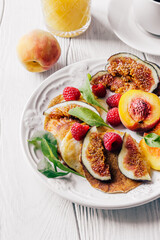 Breakfast a cup of coffee, orange juice and a plate with figs, raspberries and peaches