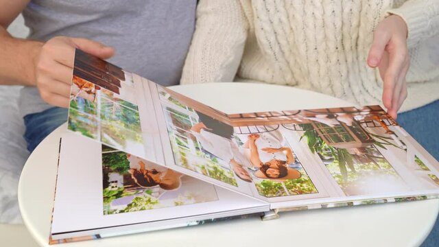 close up. couple flips through photo book from family pregnancy photo shoot.