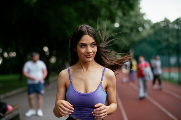 Beautiful woman training on running track. Young woman in blue sportswear listening the music.