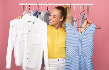 Young lady holding hangers with dress and shirt