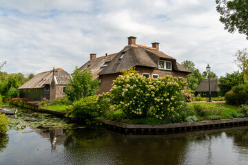 Giethoorn, The Netherlands - August 28, 2020: Houses and boat at the canal
