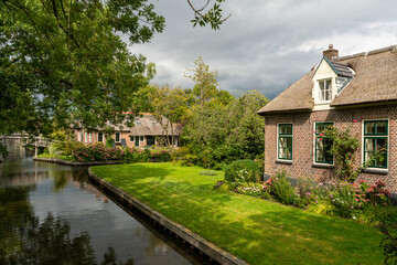 Giethoorn, The Netherlands - August 28, 2020: Houses with hydrangeas in the garden at the canal