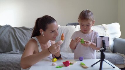 Mother with child streaming online video of unboxing wooden toys. Influencer occupation, mommy blog