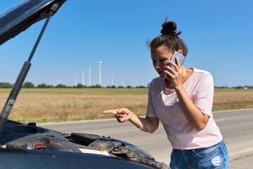 Car breakdown, unhappy woman on the road talking on mobile phone