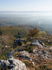 Scenic view from Kozara mountain to the valley filled with fog and smoke during a sunny day.