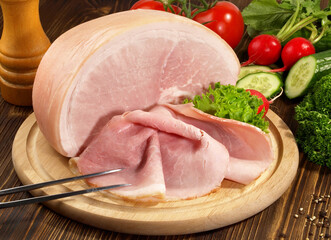 Cooked Ham with Ham Slices on a wooden Plate