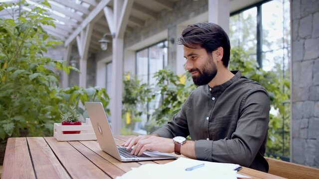 Young man with laptop sitting indoors in green office, working.