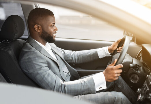 Side View Of African American Man In Suit Driving Car