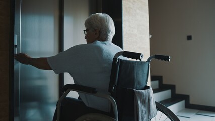 old disabled woman calling a lift in the hospital hall. High quality photo © CameraCraft