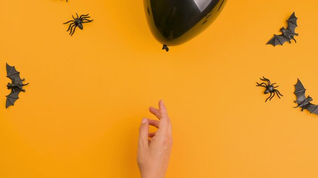 Happy halloween! A black ball flies out of the hands on an orange background. Free space for text. Stop motion. High quality FullHD footage