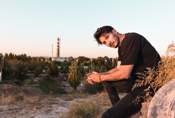 portrait of a young man in a black outfit in an industrial zone