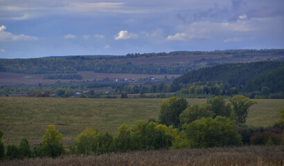 Heavy rain clouds over village fields and copses. Autumn bad weather in the foothills of the Western Urals.