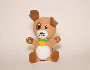 A toy brown dog sits on a white background. Toys for children, soft plush animals.