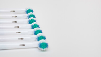 Parts of an electric toothbrush are laid out in a row, white background, free space for text.