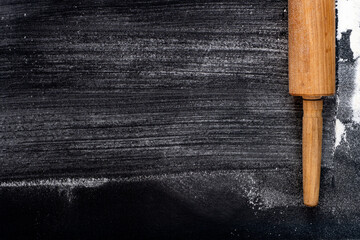 Selective focus. Rolling pin and Wheat Flour on a dark background. Free space for text.