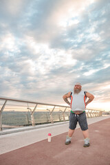 Fat caucasian bearded and bold man with tattoos is doing morning exercses to loose his weight