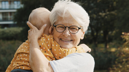 Happy grandmother holding her grandson baby in the nature. High quality photo