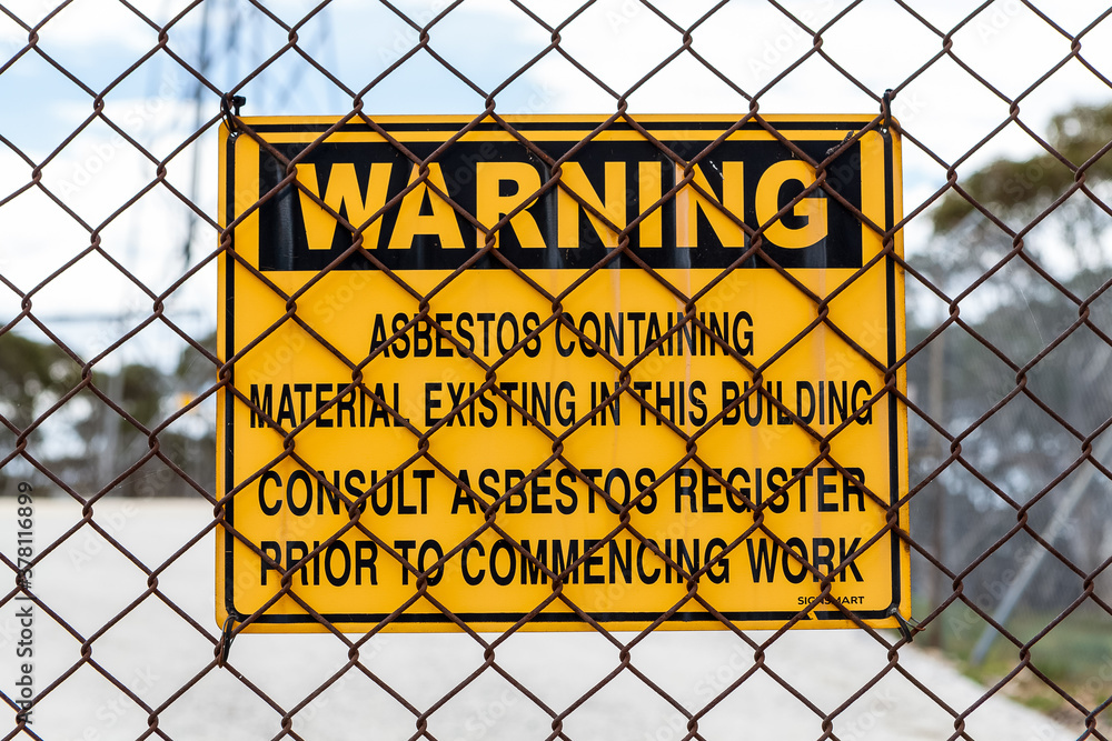 Wall mural an asbestos warning sign attached to a rusty wire fence alerting those entering to the possible dang