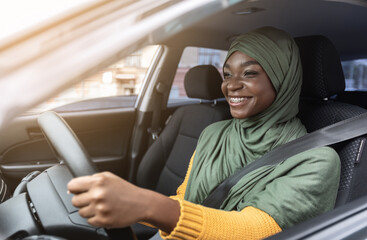 Happy Black Muslim Woman In Hijab Driving Car With Fasten Seat Belt