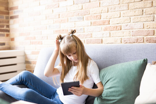 Teenage schoolgirl doing homework with digital tablet at home. A child using gadgets to study. Education and distance learning of children. Homeschooling during quarantine. Stay home fun.