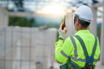 Elderly male construction engineer wearing safety clothes Carrying a radio communication for radio...