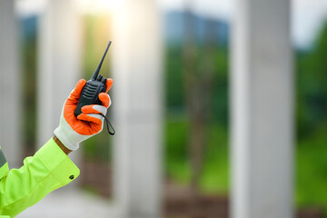 A close-up of a construction worker holding a radio communication for use of a construction radio.